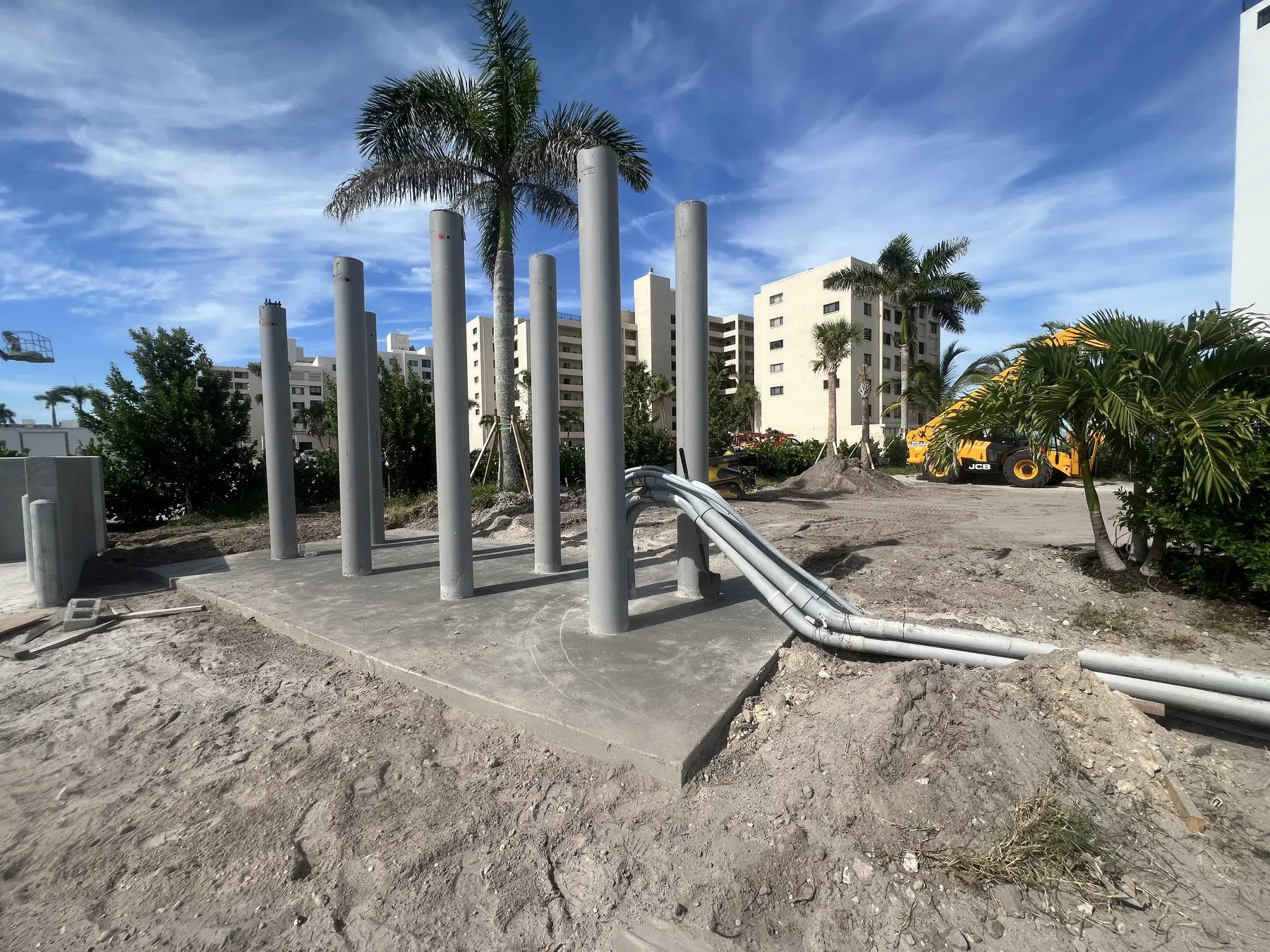 Concrete slab with vertical piles and site equipment in the background